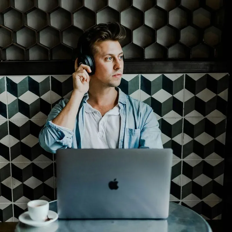 Man working on laptop at cafe, wearing headphones